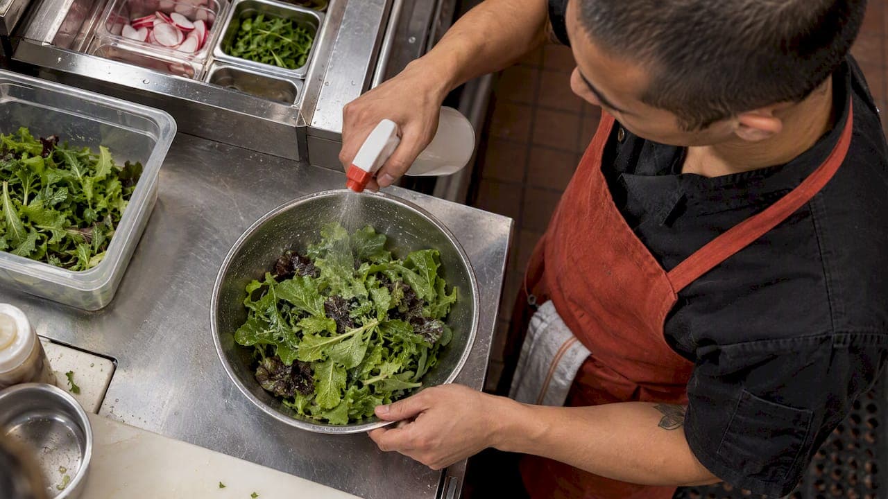 Cook misting leafy greens before food photography